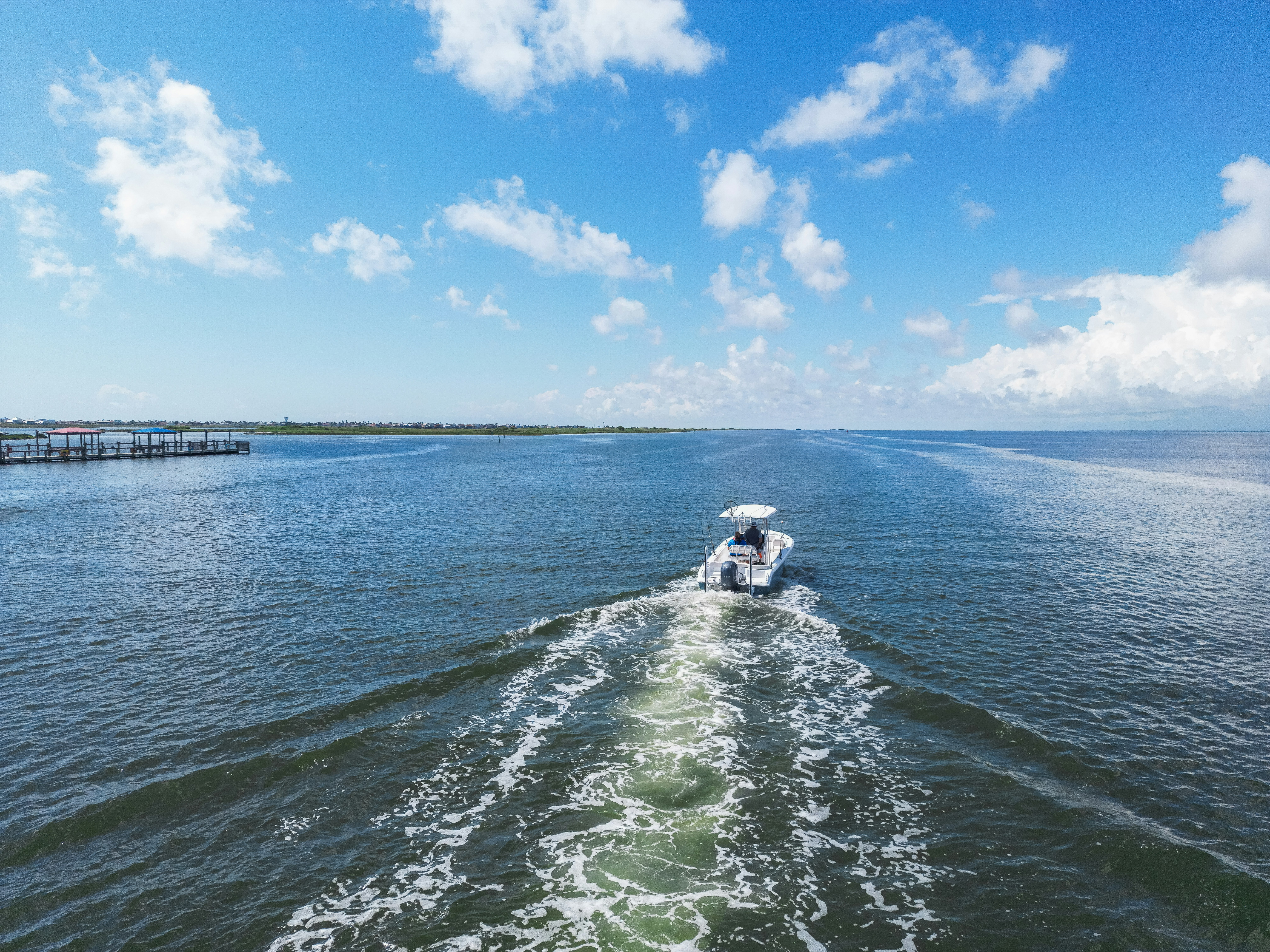 A boat cruises across the beautiful, blue water.