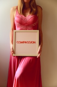 Woman holds a sign that reads "compassion."