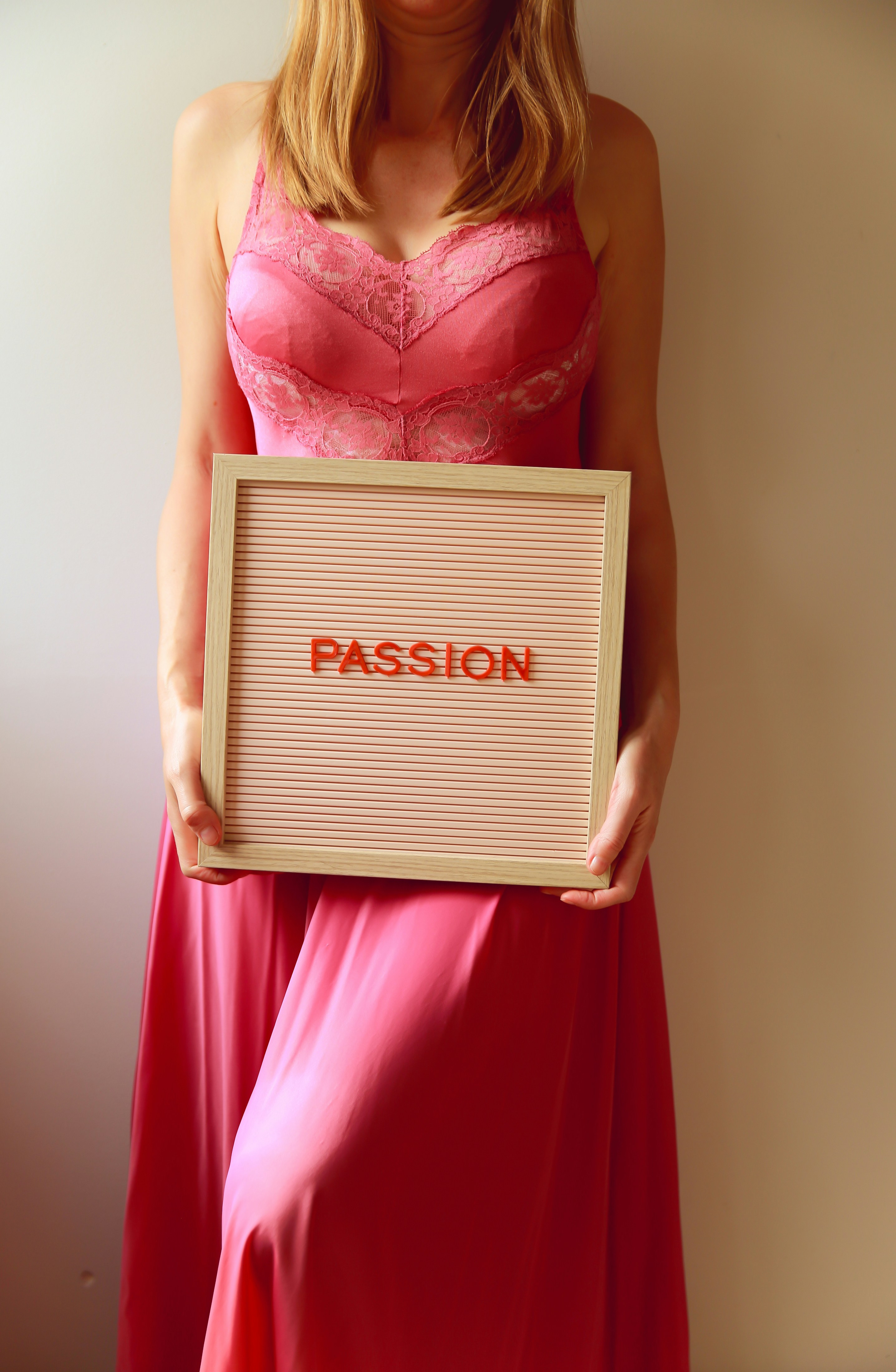 Woman in pink dress holds a sign that reads "passion".