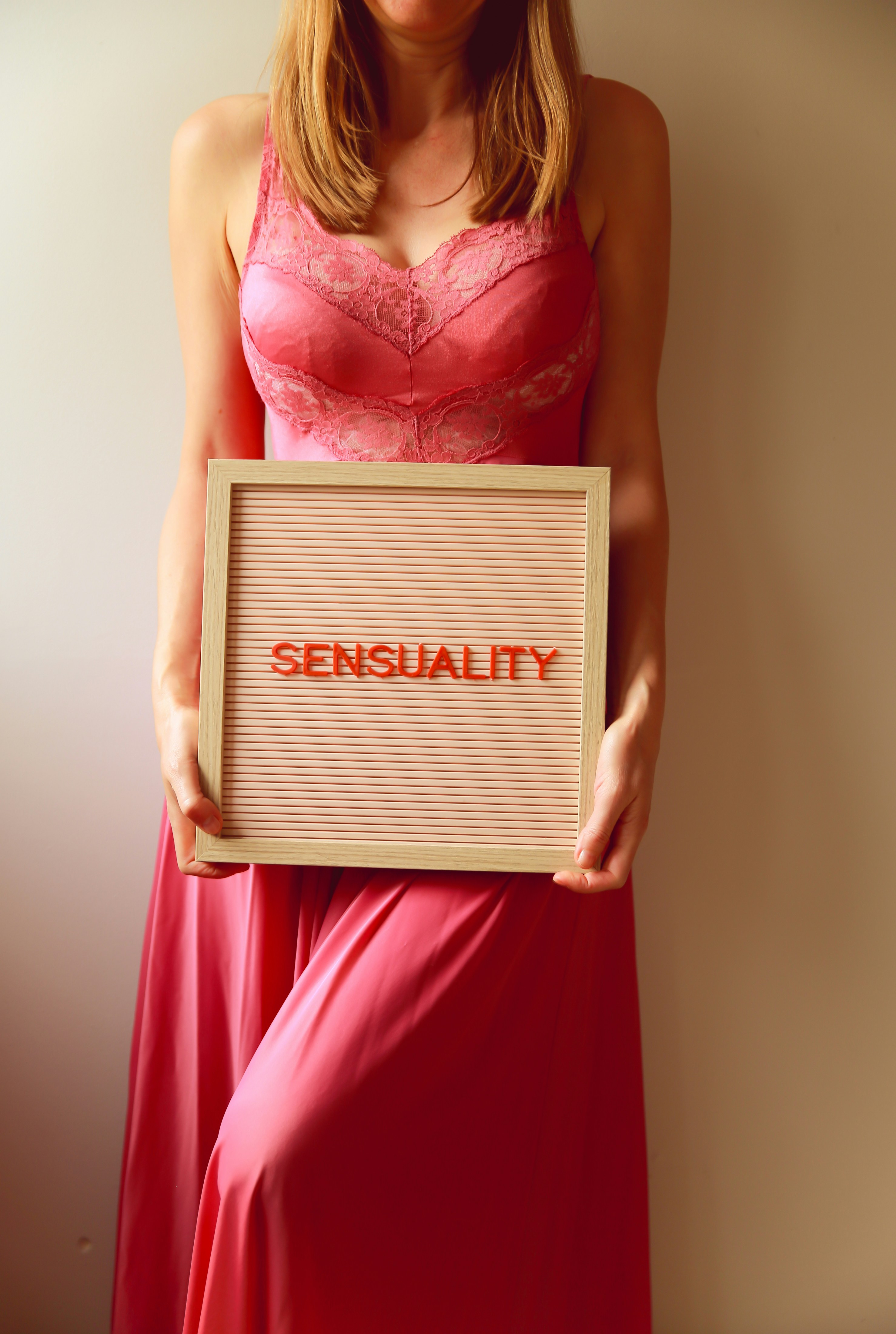 Woman in pink holding a sign that says "sensuality."