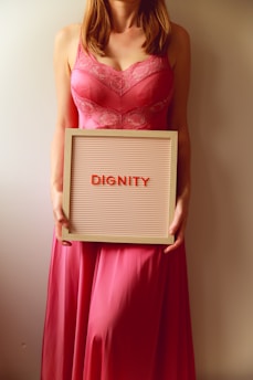Woman in pink dress holds sign with "dignity".