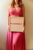 Woman holds a sign reading "accountability."