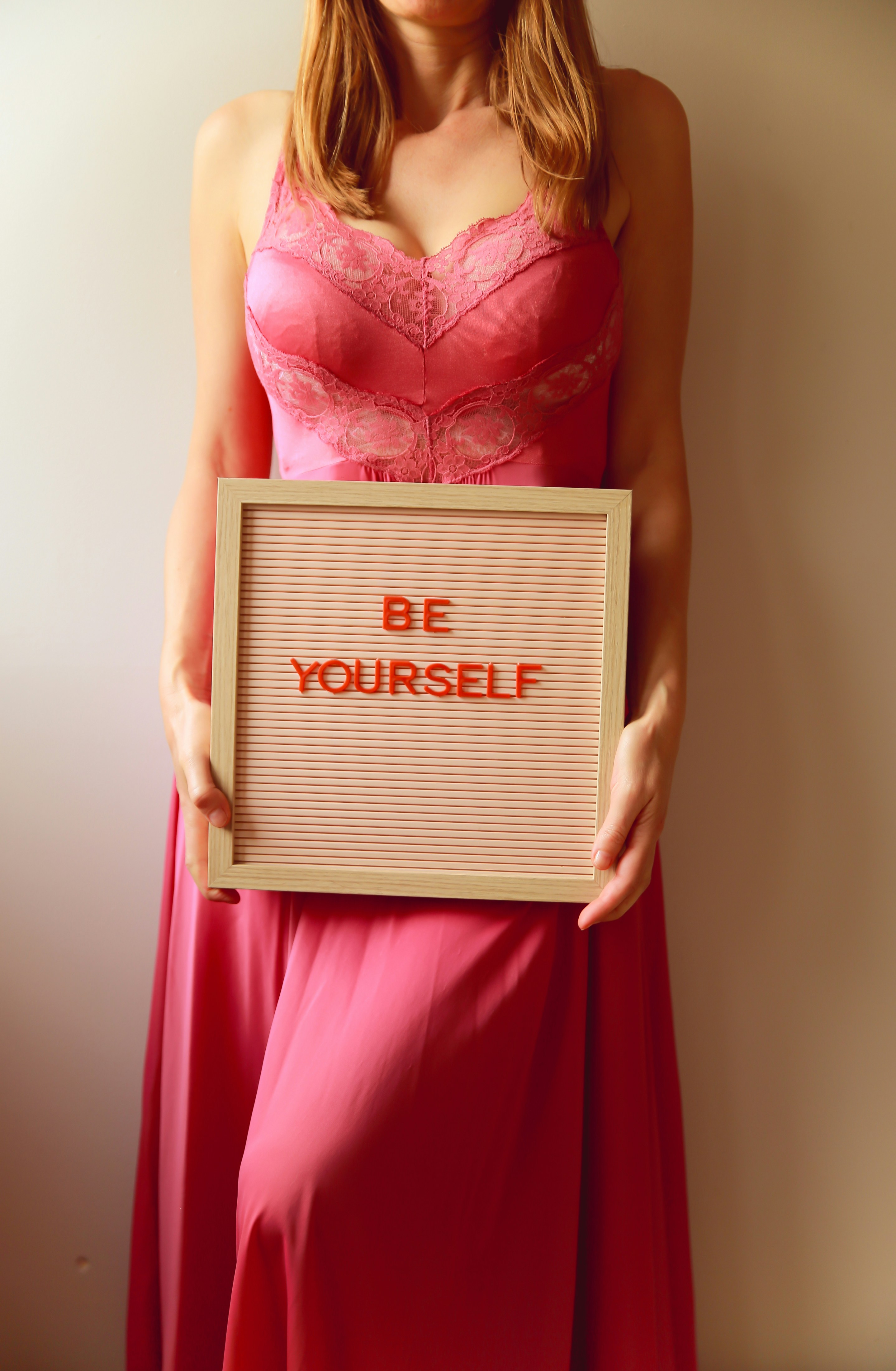 Woman holds a sign that reads, "be yourself."