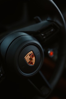 The porsche steering wheel is in close up.