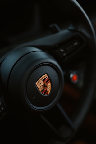 The porsche steering wheel is in close up.