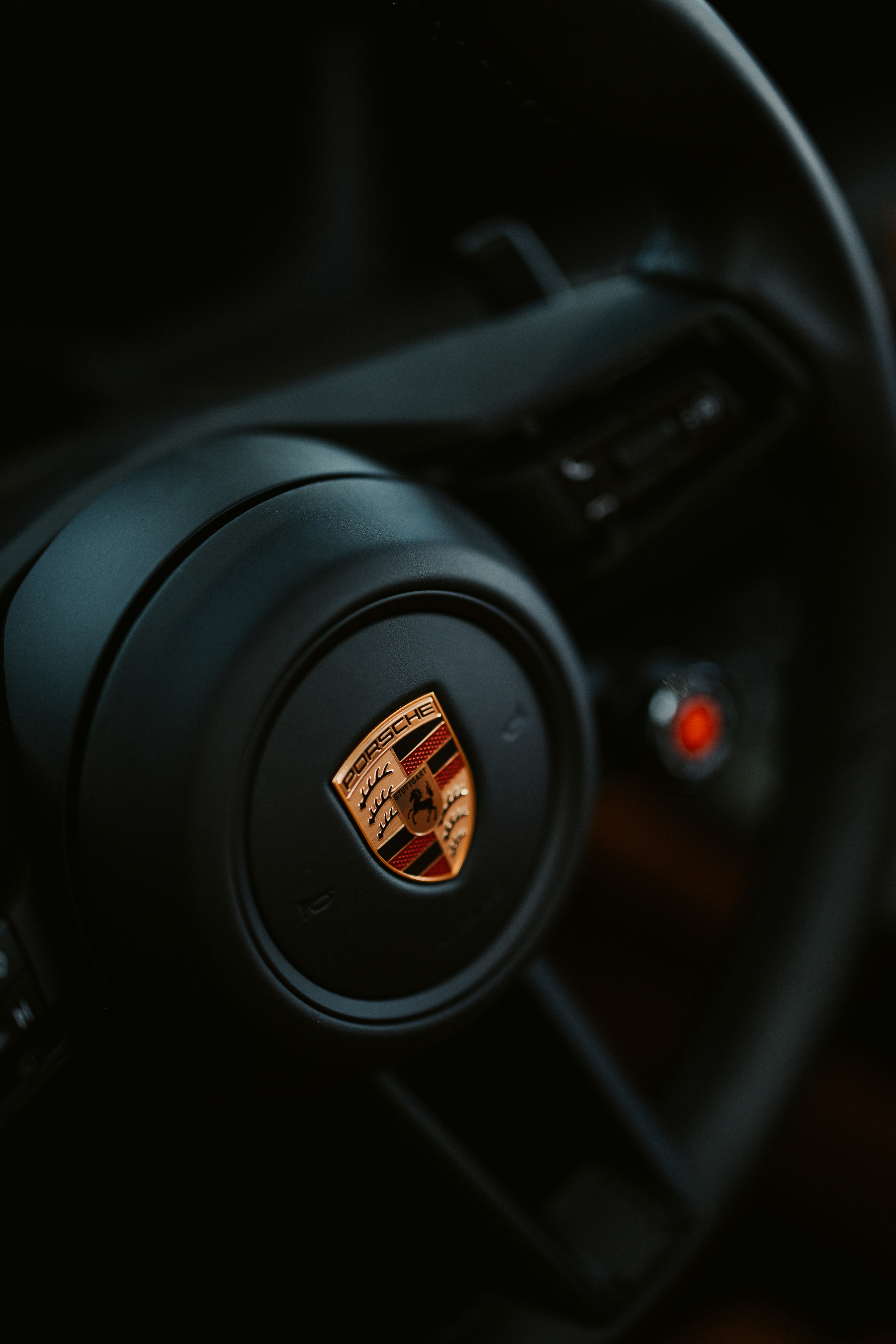 The porsche steering wheel is in close up.