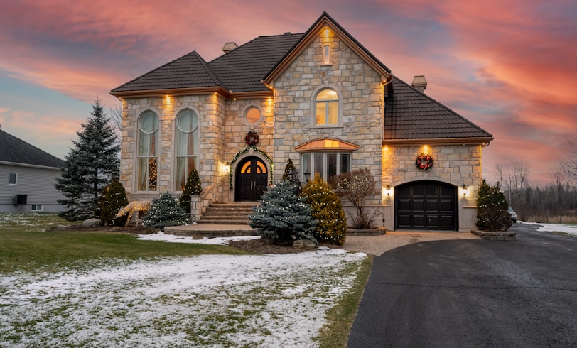 Luxurious stone house at sunset with a driveway.