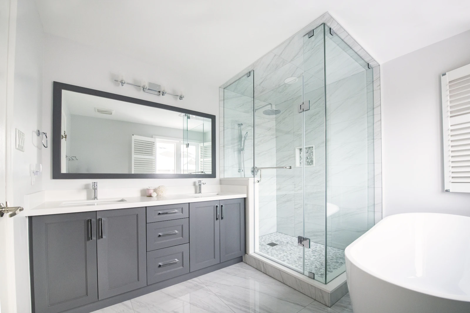 Bathroom with a glass shower, freestanding tub, and gray vanity