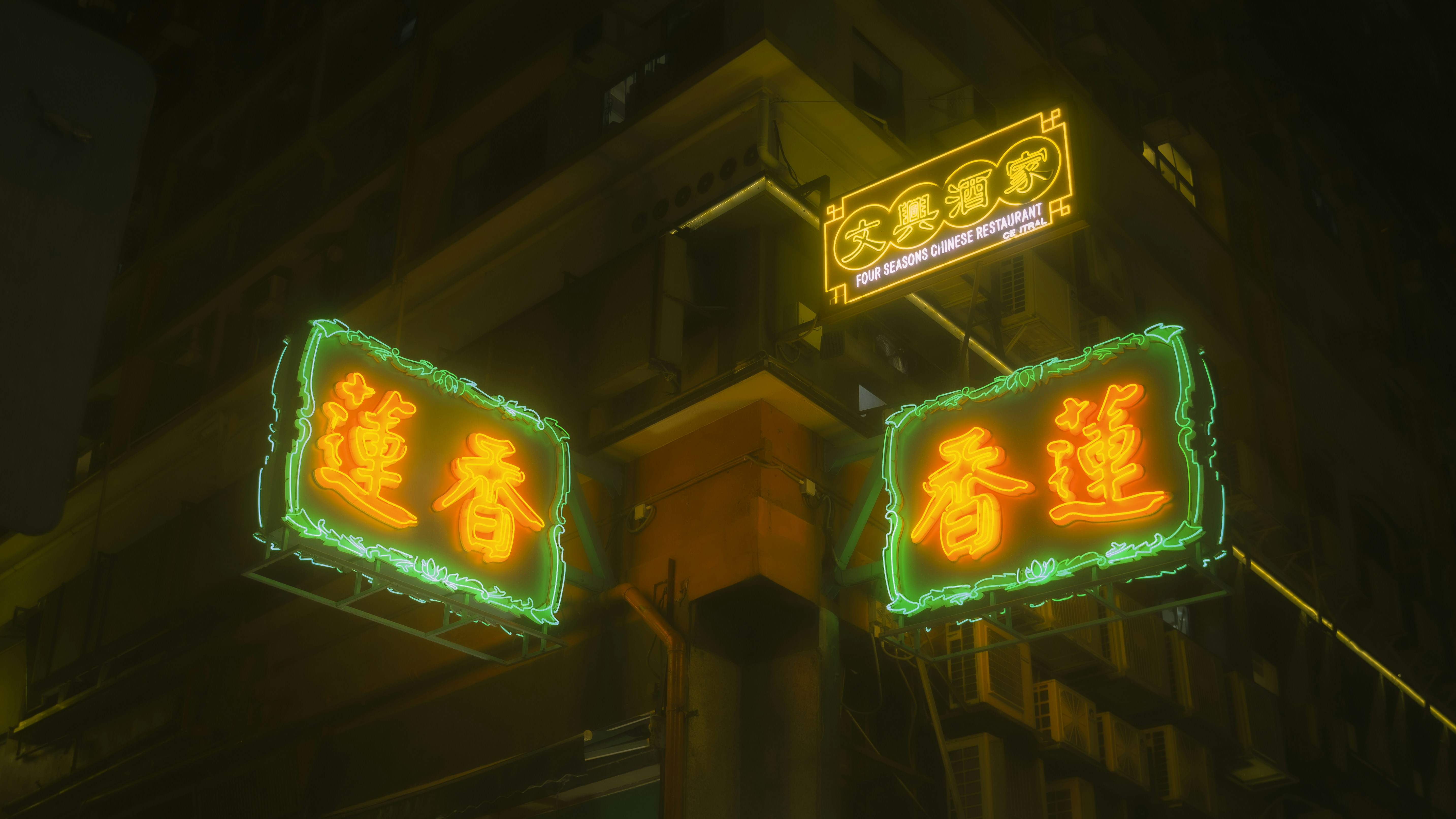 Neon signs illuminate a street corner at night.