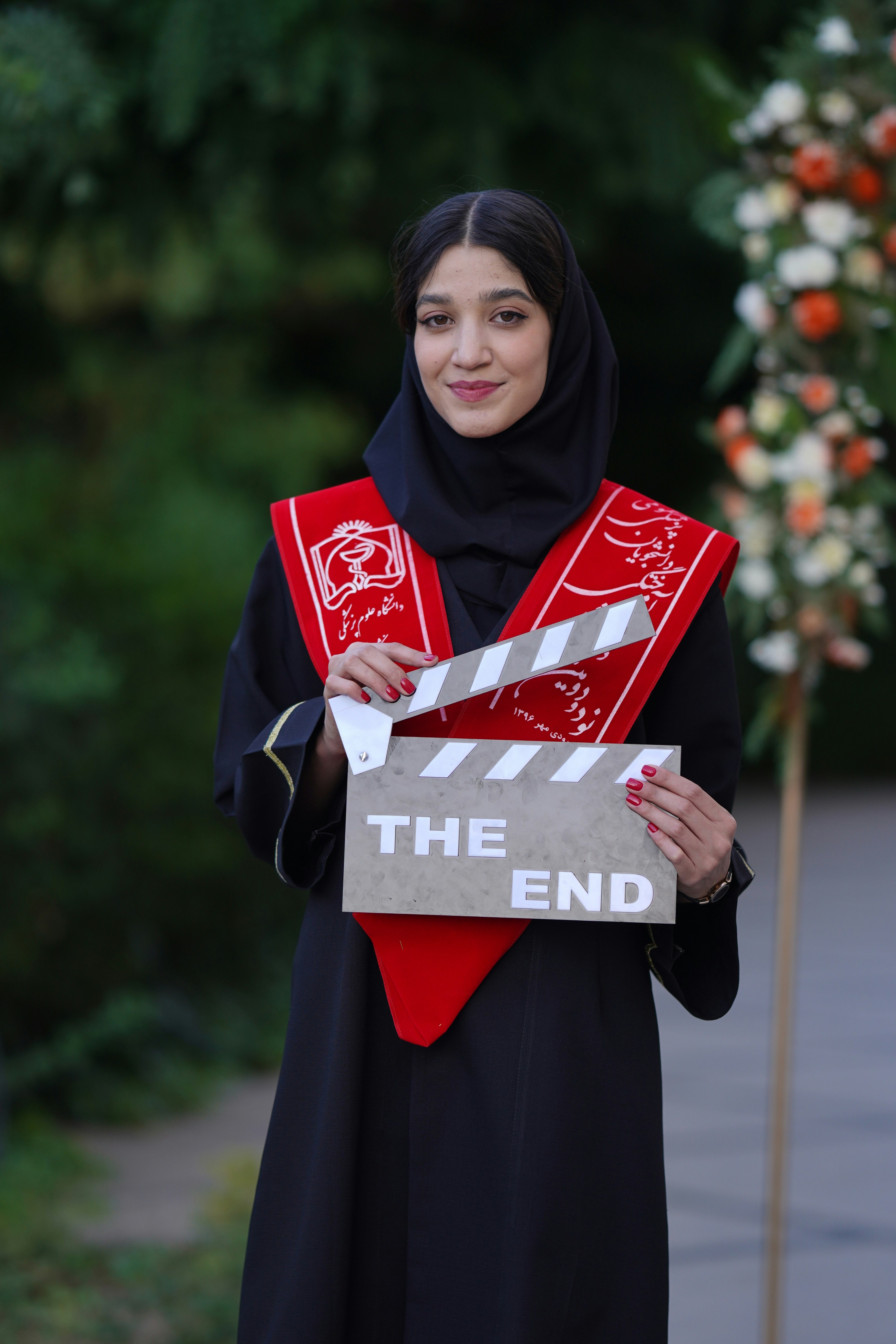 Graduating student holds a clapperboard that reads \