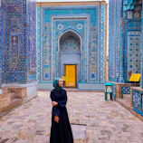 Woman poses in front of stunning blue architecture.