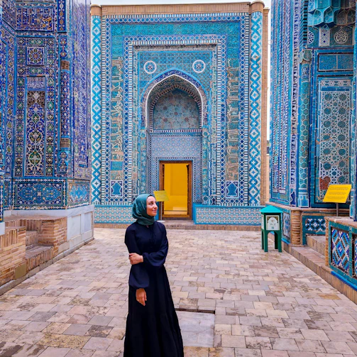 Woman poses in front of stunning blue architecture.