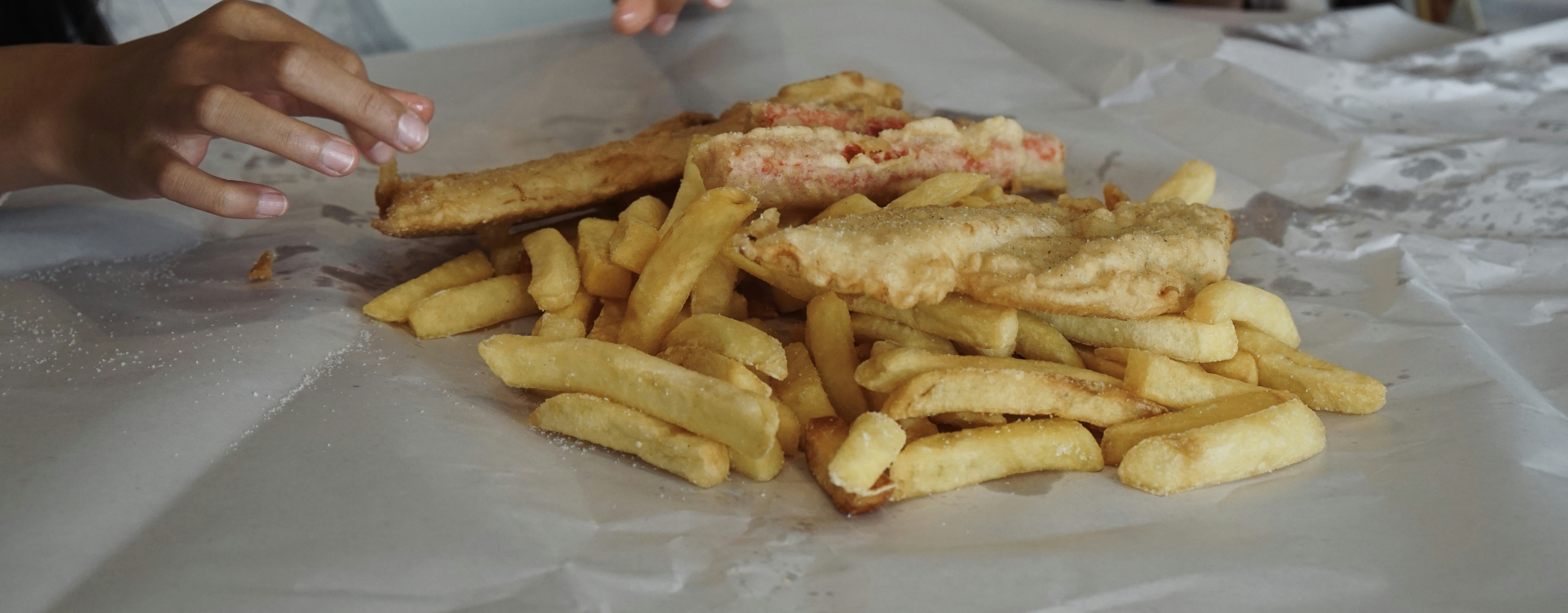 Fish, chips and a sausage on a paper.