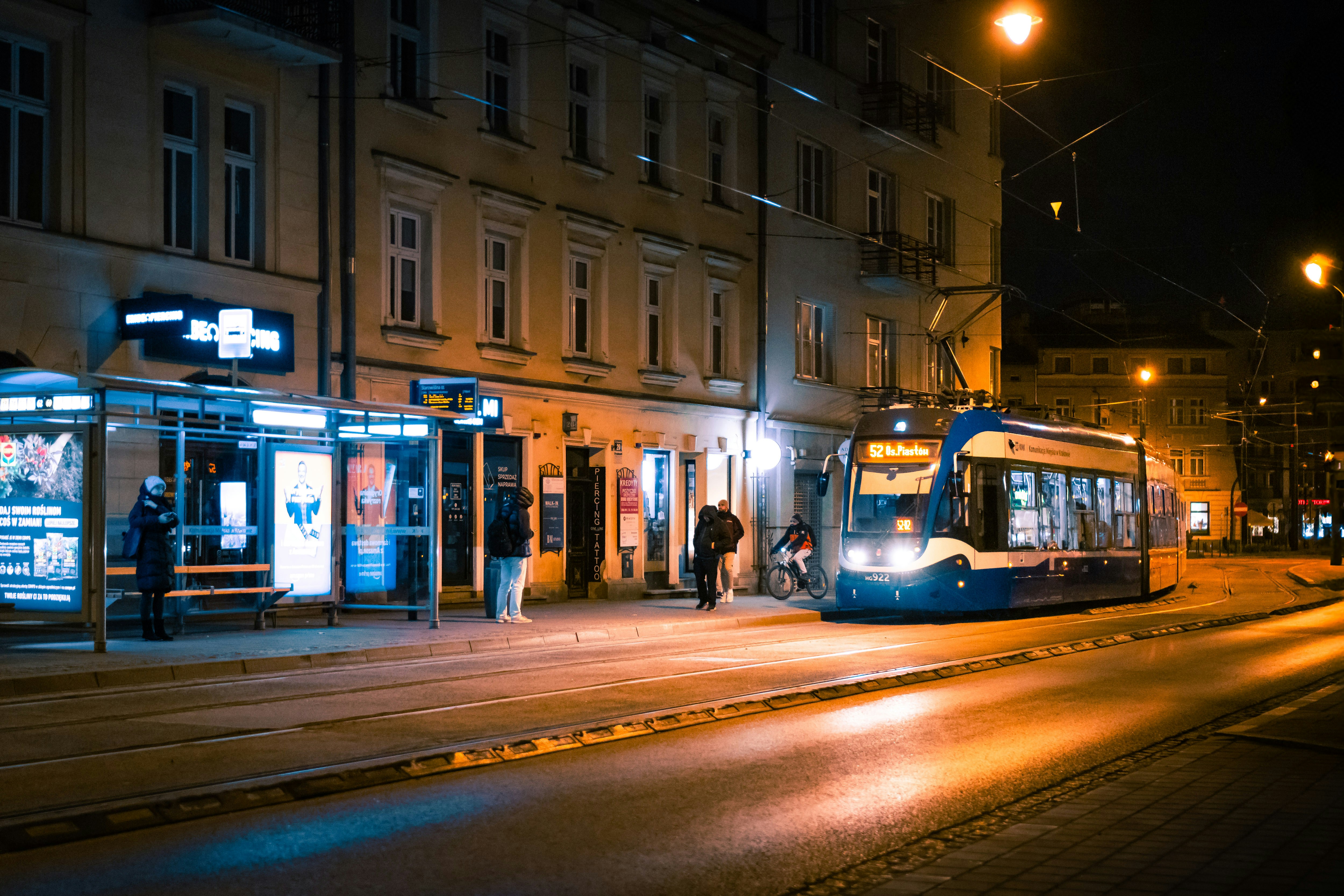 A tram approaches a stop on a city street at night.