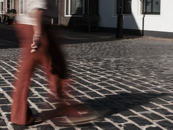Person walking quickly across cobblestone street.