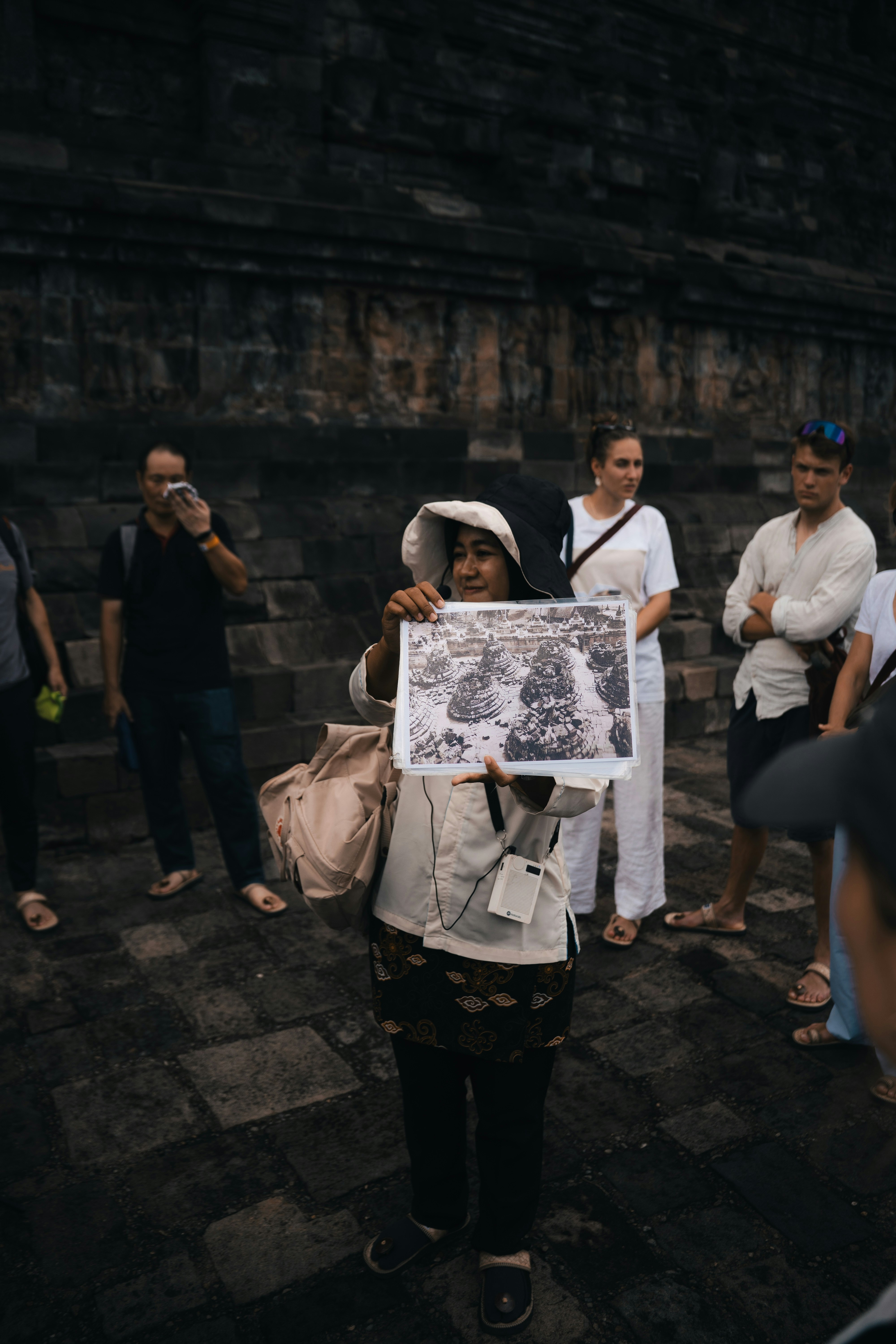 A tour guide shows visitors a picture of a temple.
