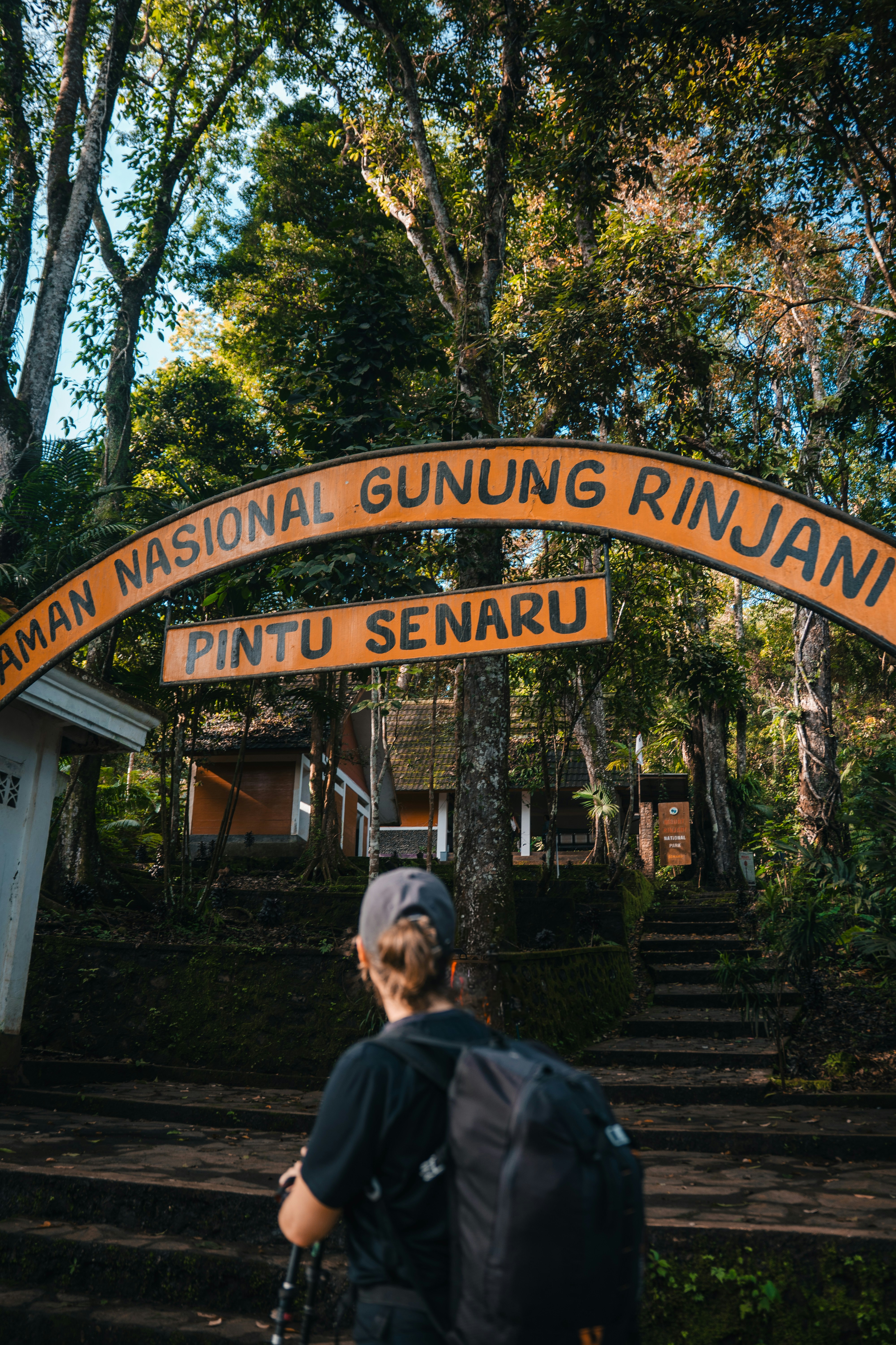 Caminhante se aproxima de uma placa que diz "gunung rinjani".