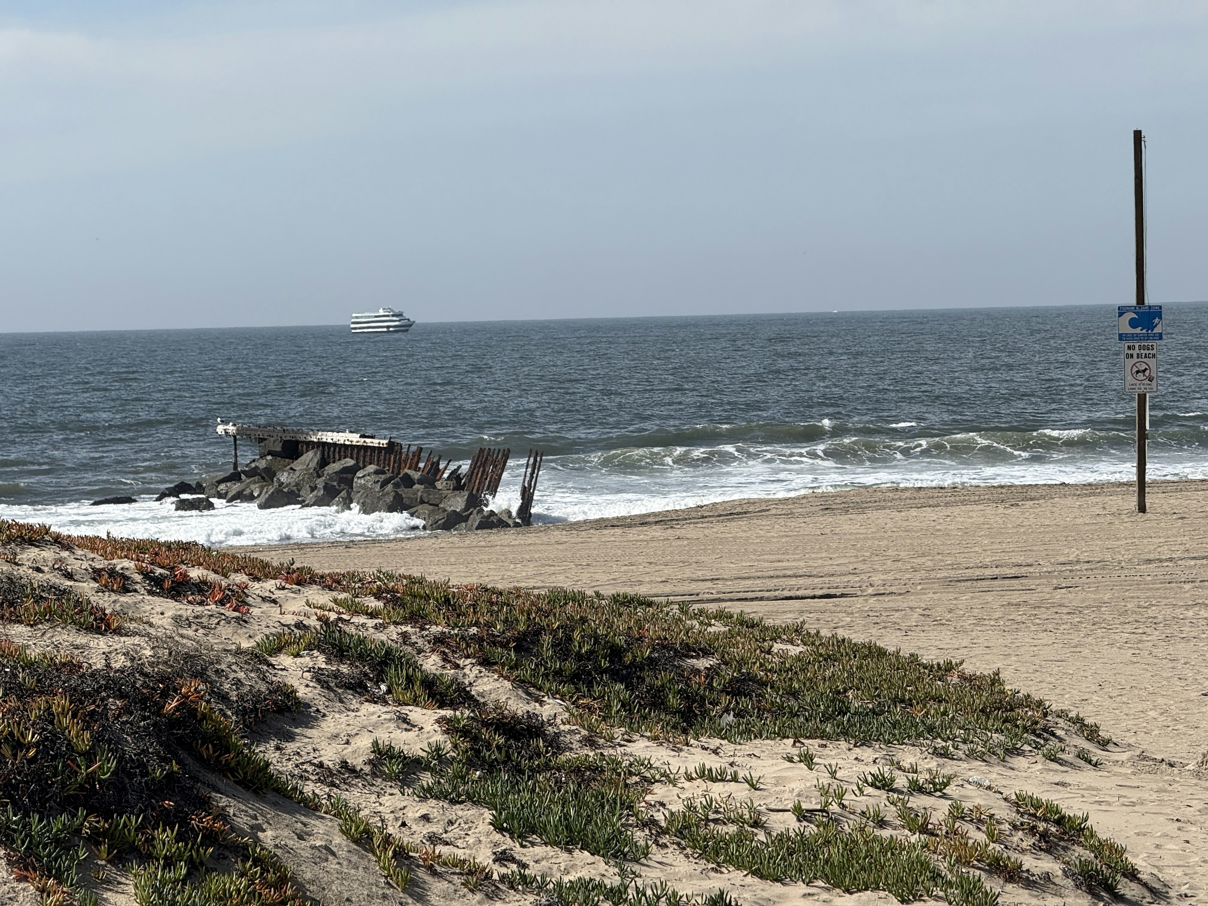 A shipwreck lies on a sandy beach.