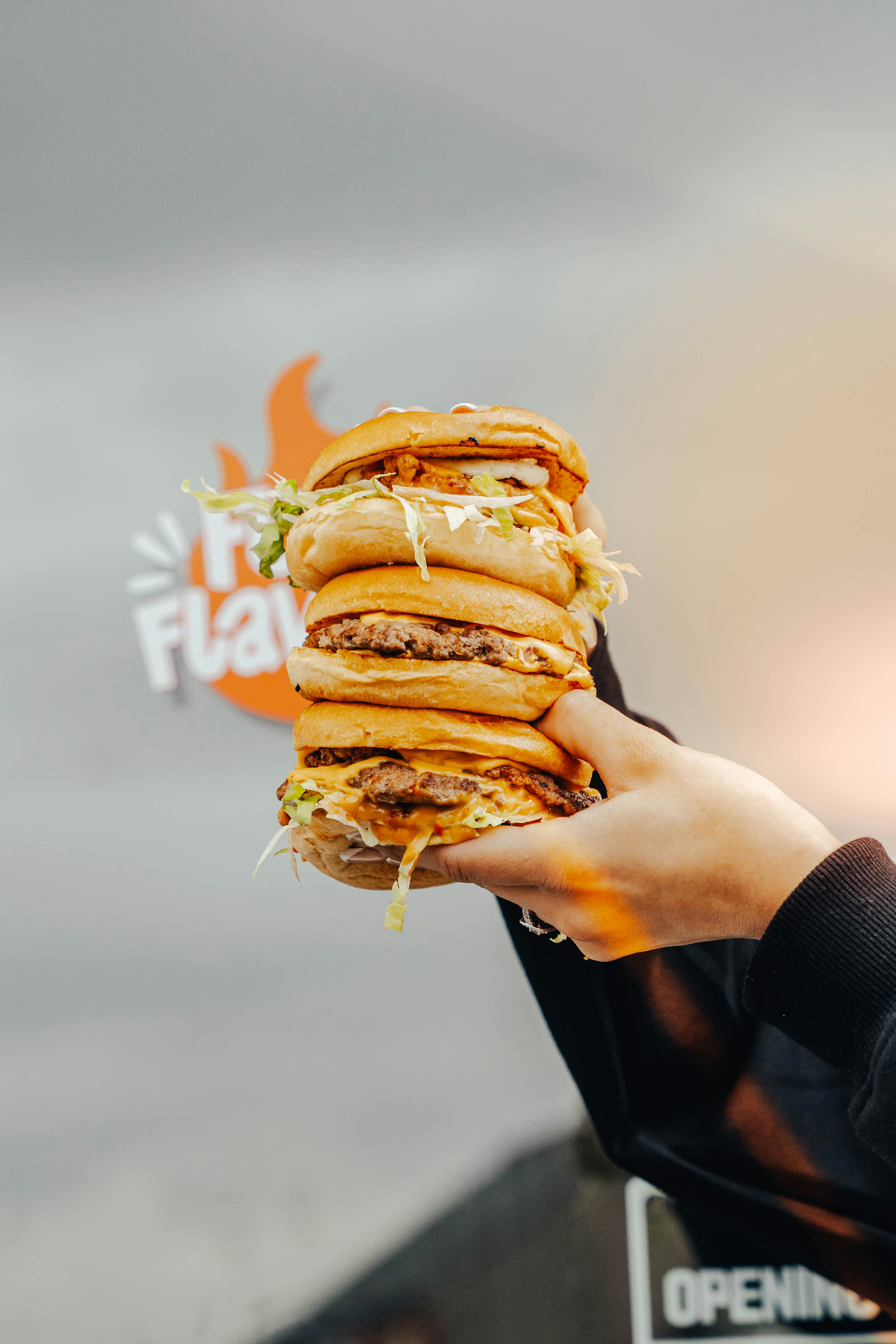 A person holds a stack of delicious burgers.