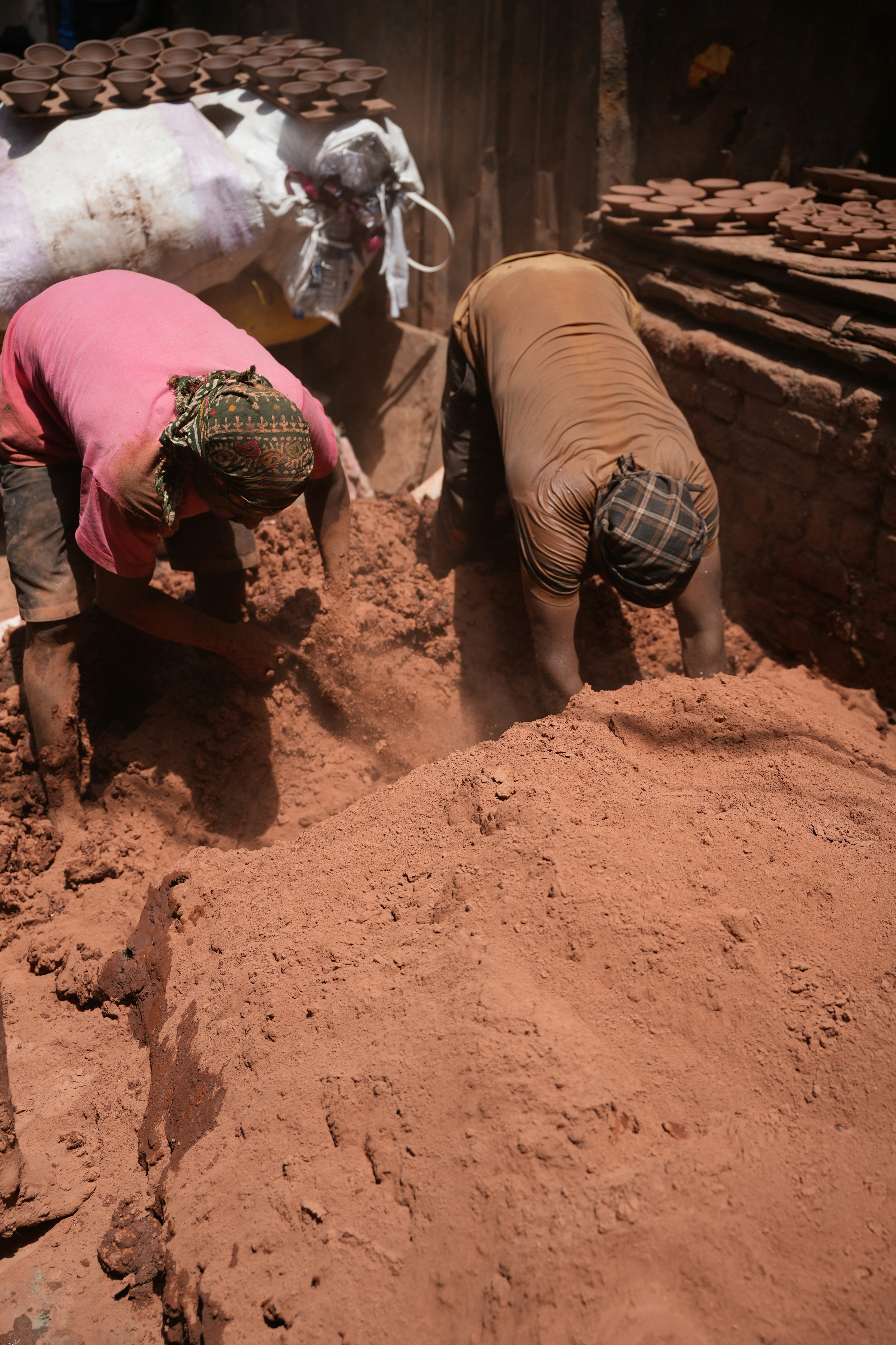 Workers are laboring, likely mixing mud or clay.