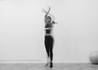 A blurry dancer performs in a white room.