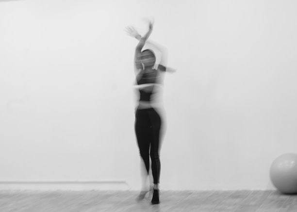 A blurry dancer performs in a white room.