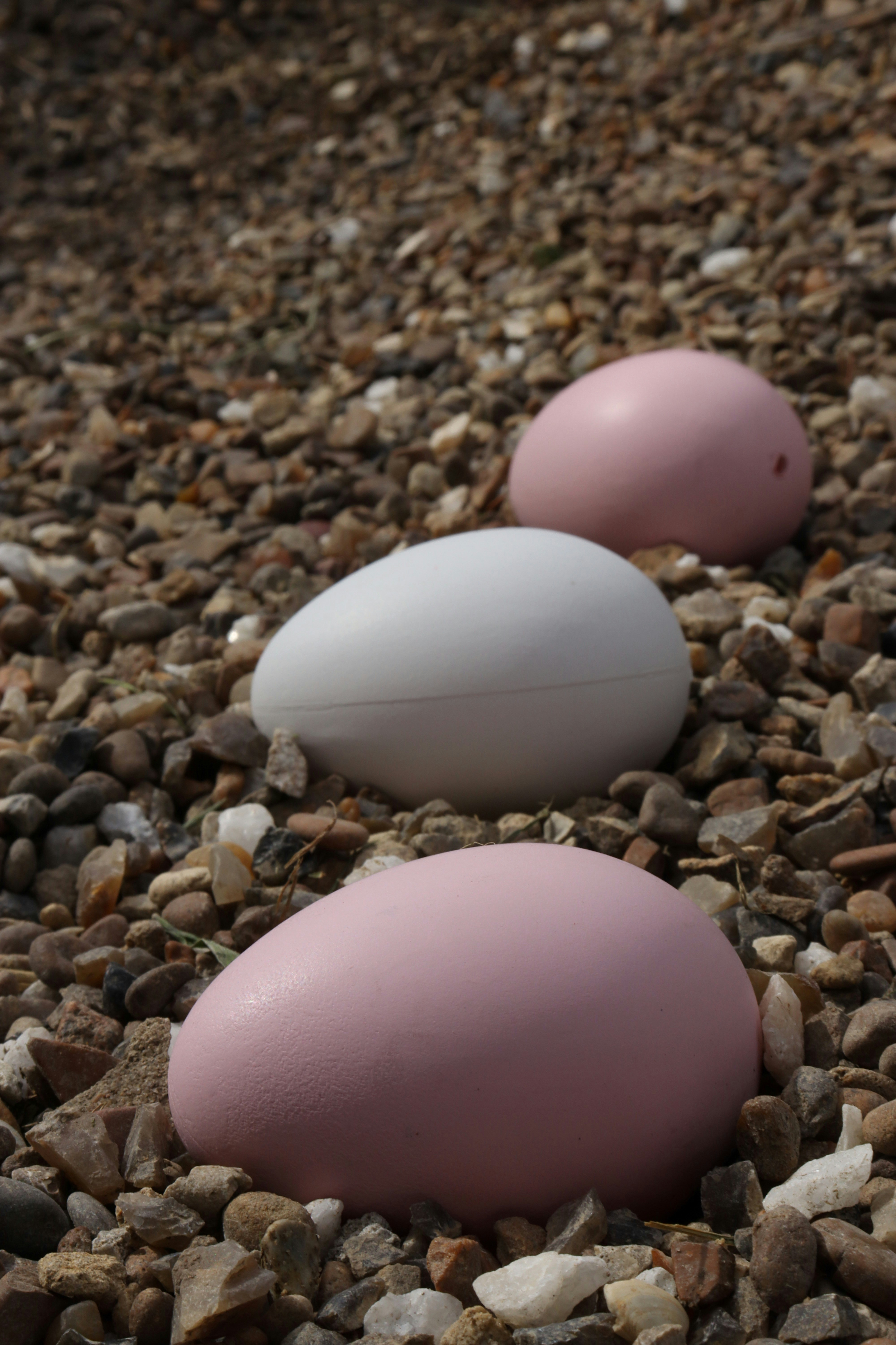 Three painted eggs sit on a bed of stones.