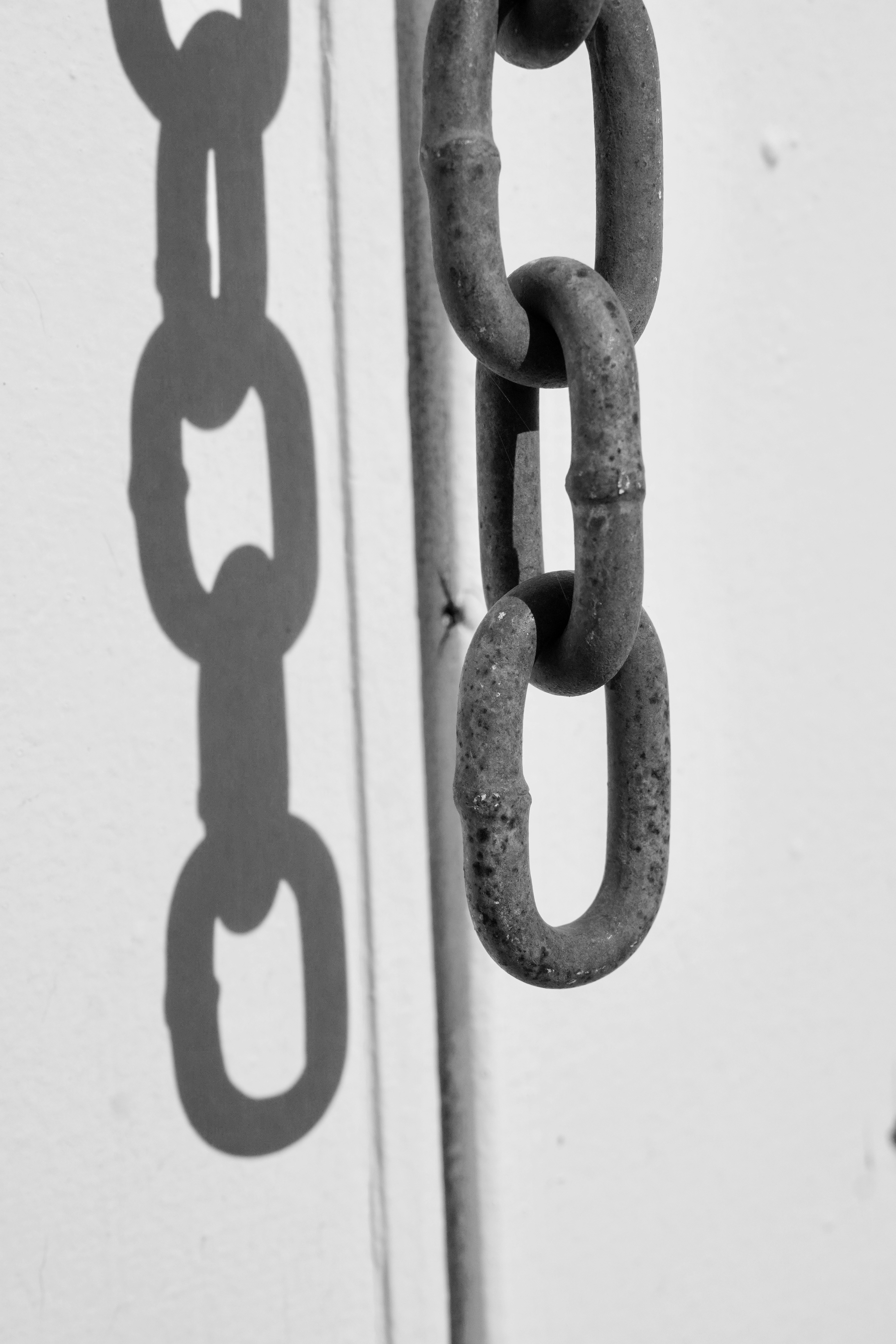 A rusty chain and its shadow hang.