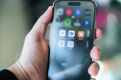 A hand holds a smartphone with various apps