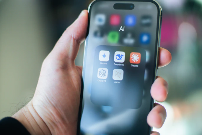 A hand holds a smartphone with various apps.
