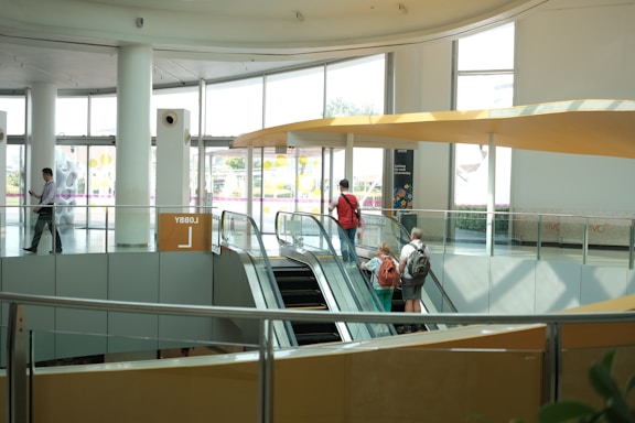 People ride escalators in a modern building.