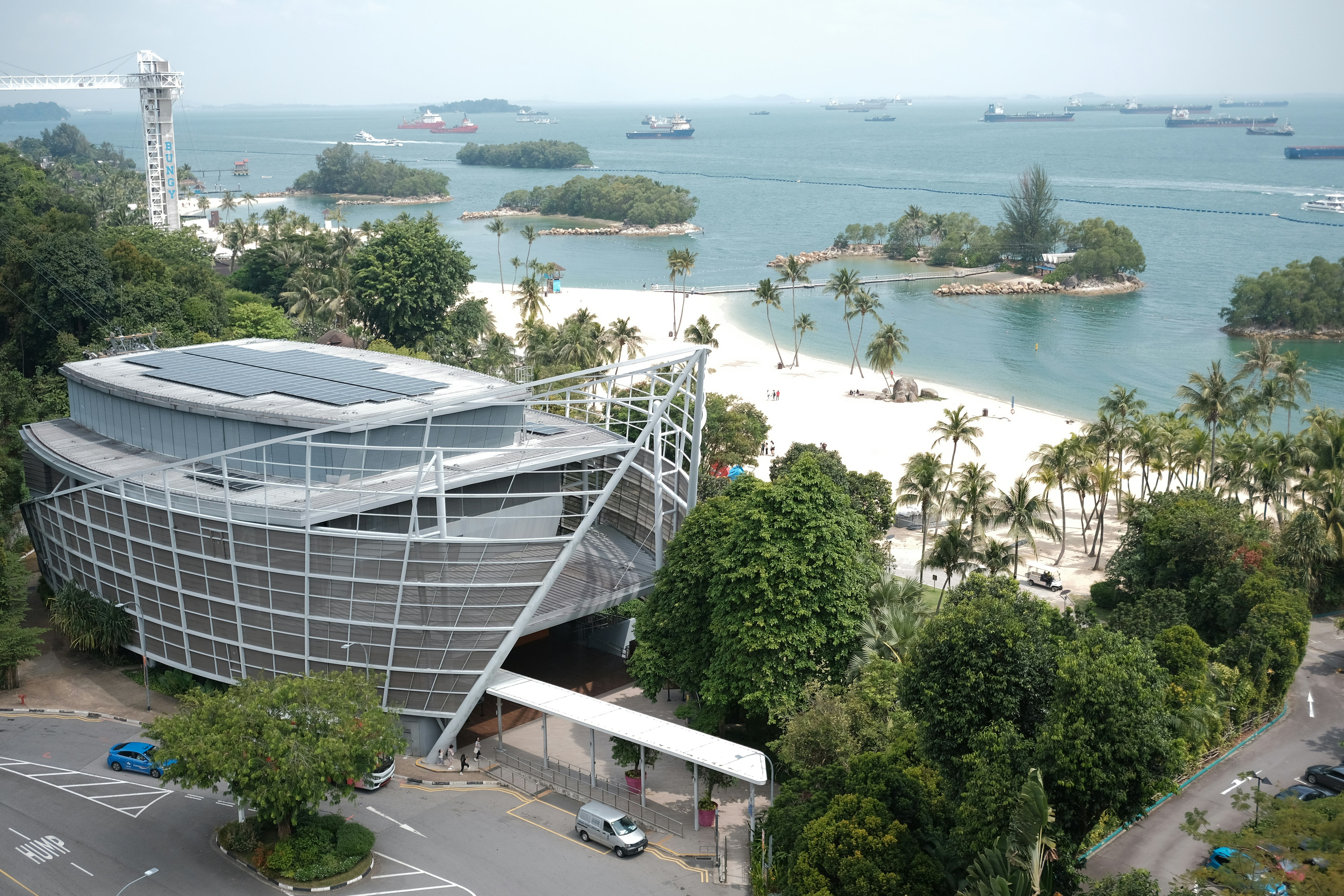 A modern building overlooks a beautiful beach and ocean.