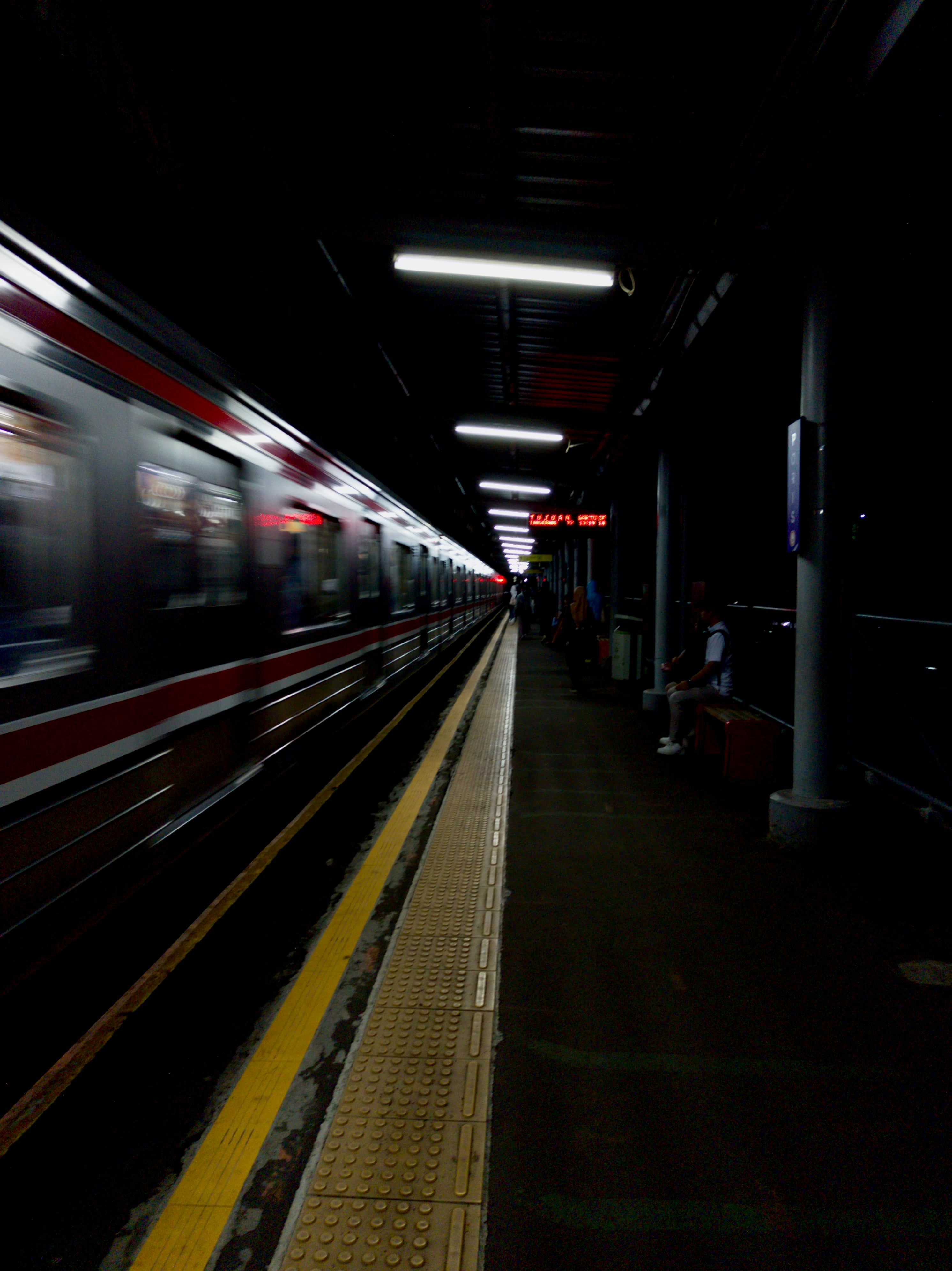 A train rushes through a dimly lit station.