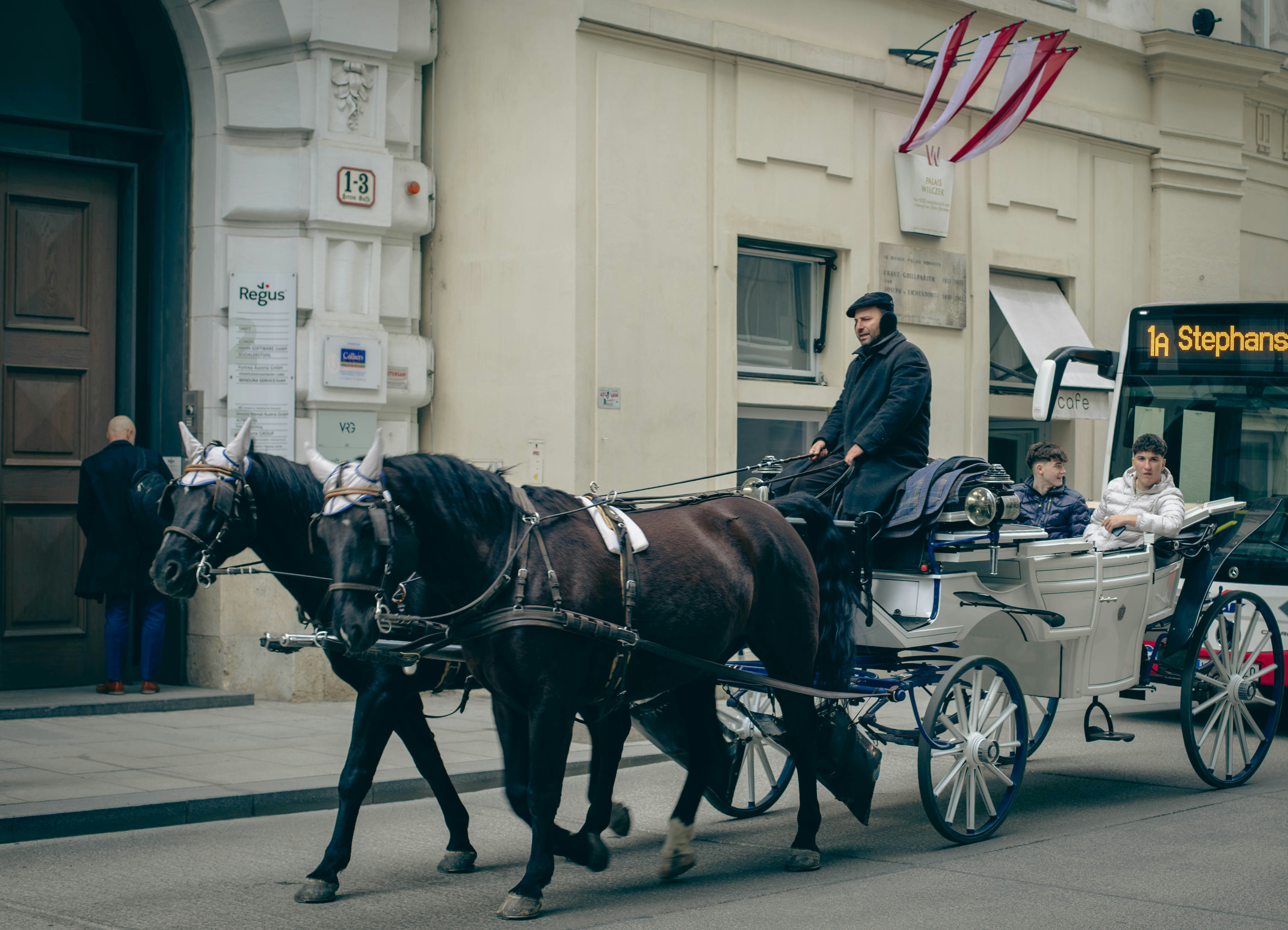 A horse-drawn carriage rides down a city street.