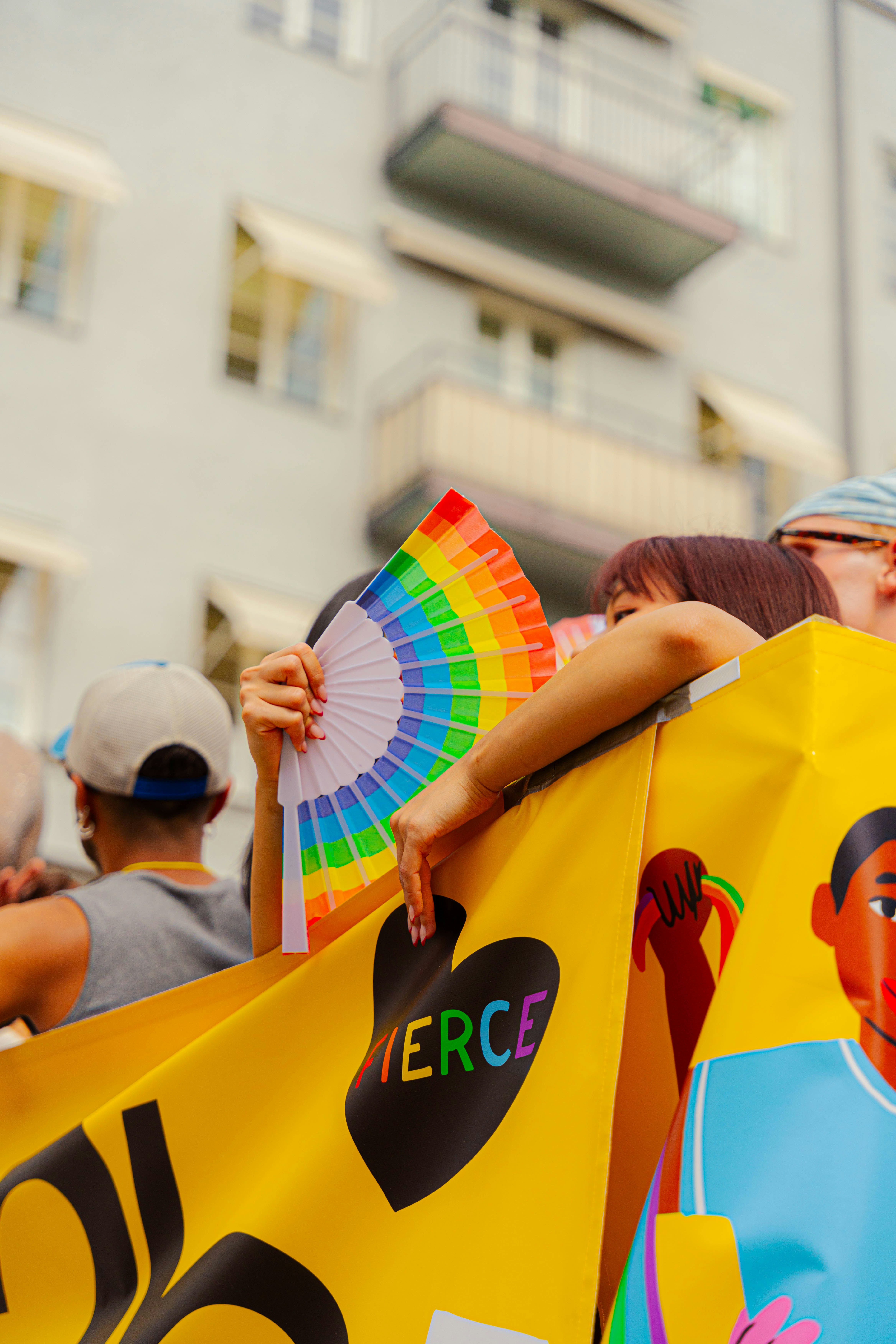 People celebrate pride, holding a rainbow fan.