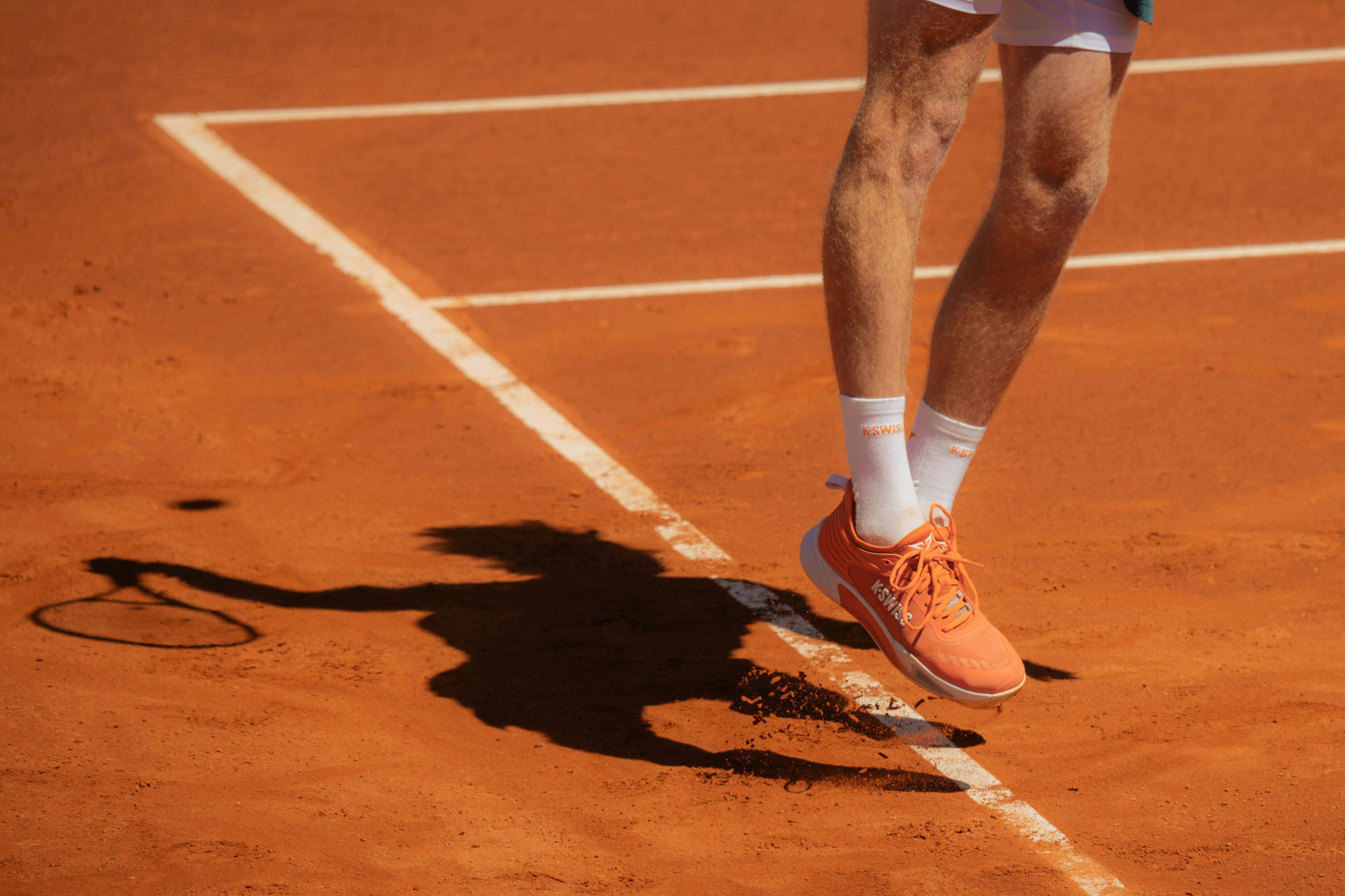 A tennis player jumps to serve the ball.