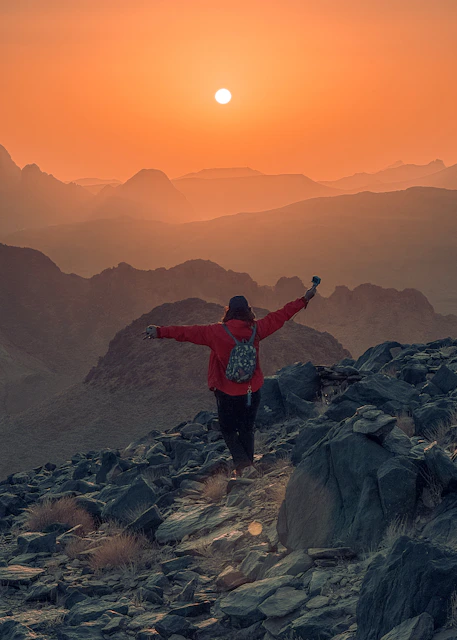 Tourist standing on the Tassili plateau, enjoying the sunset while taking photos.