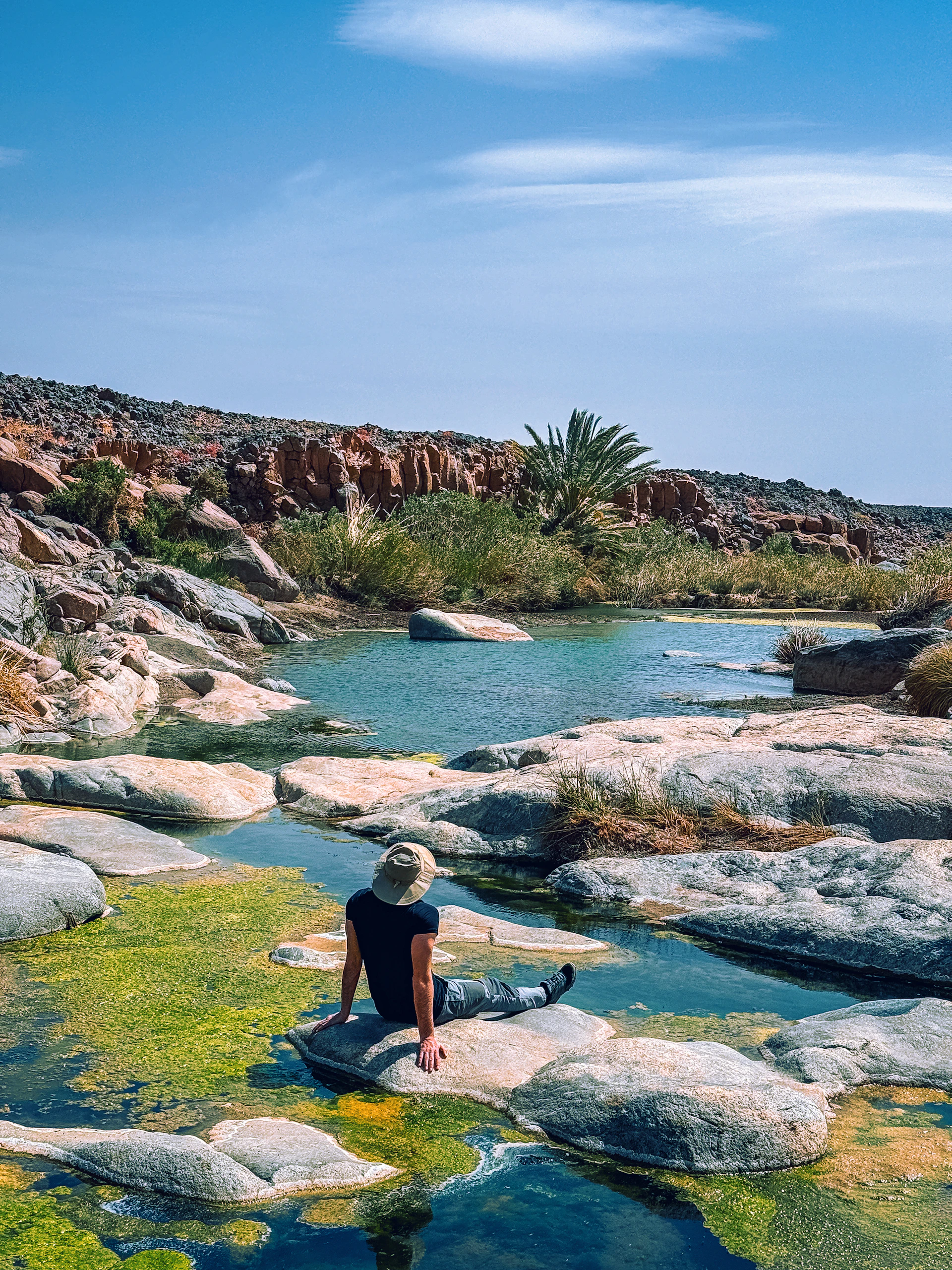 A person sits by a stunning, natural pool