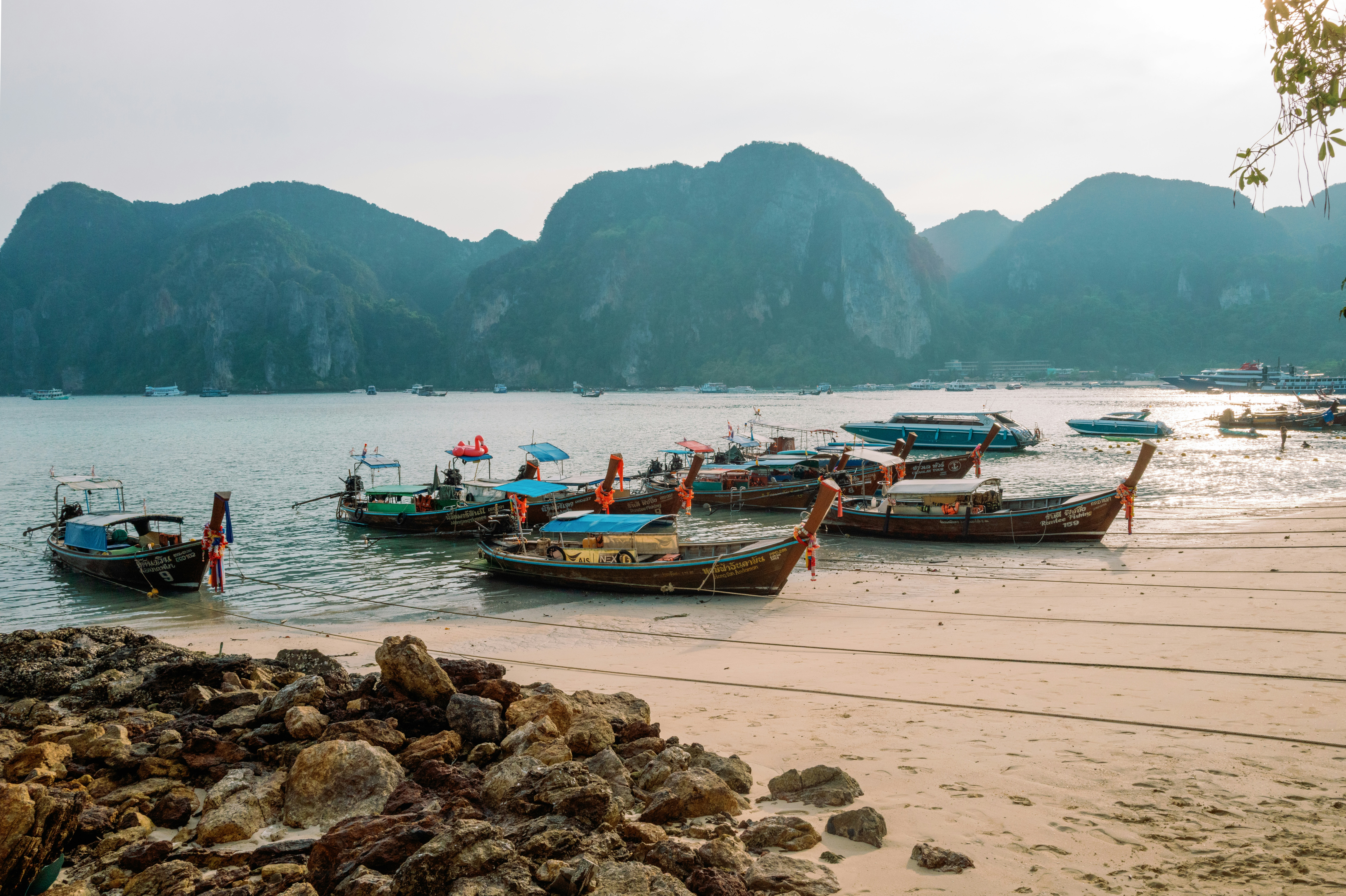 Boats are beached on a shore, with mountains behind.