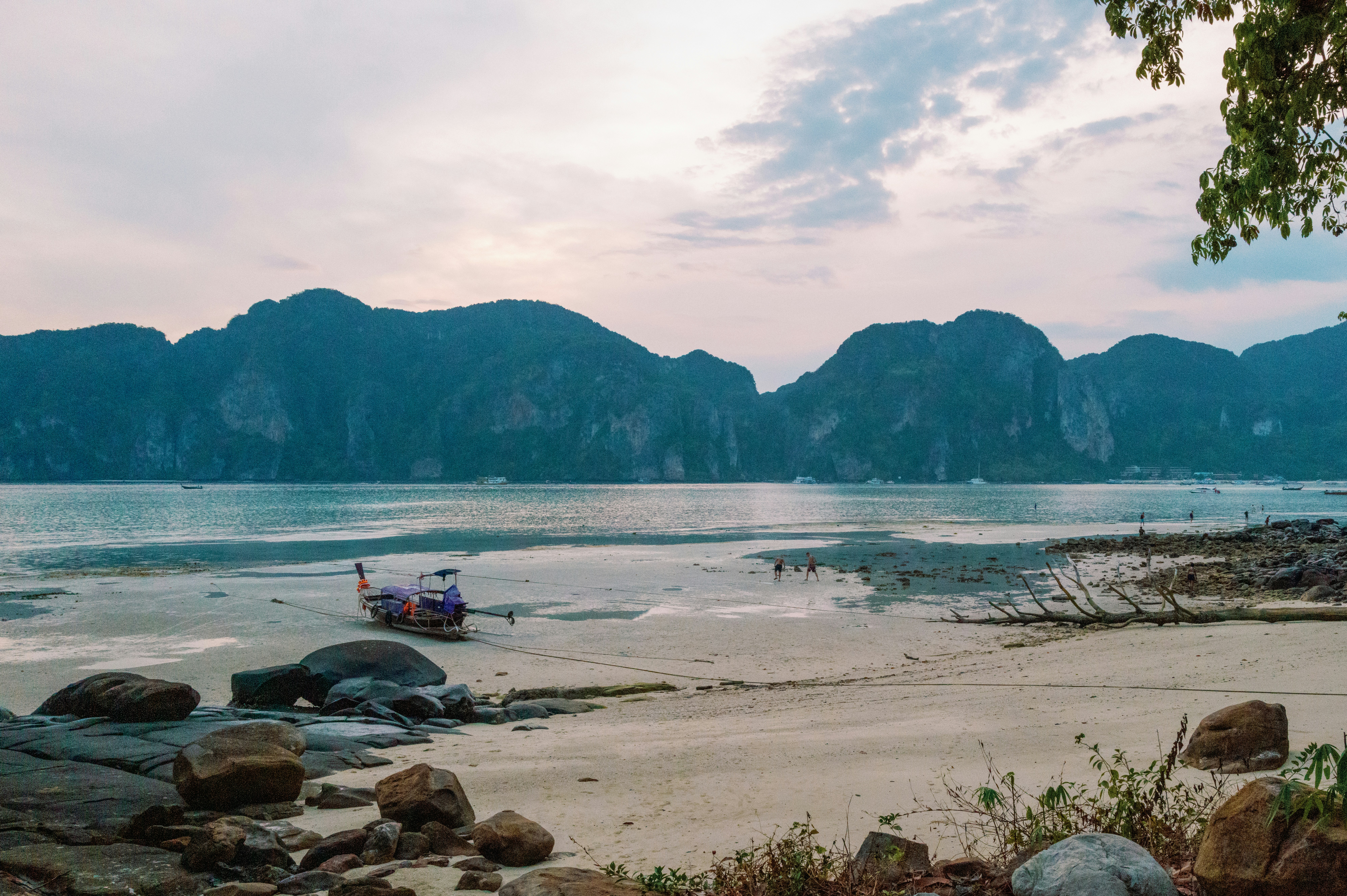 A boat sits on a beach in front of mountains.