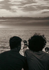 Two people admire the ocean and dramatic sky.