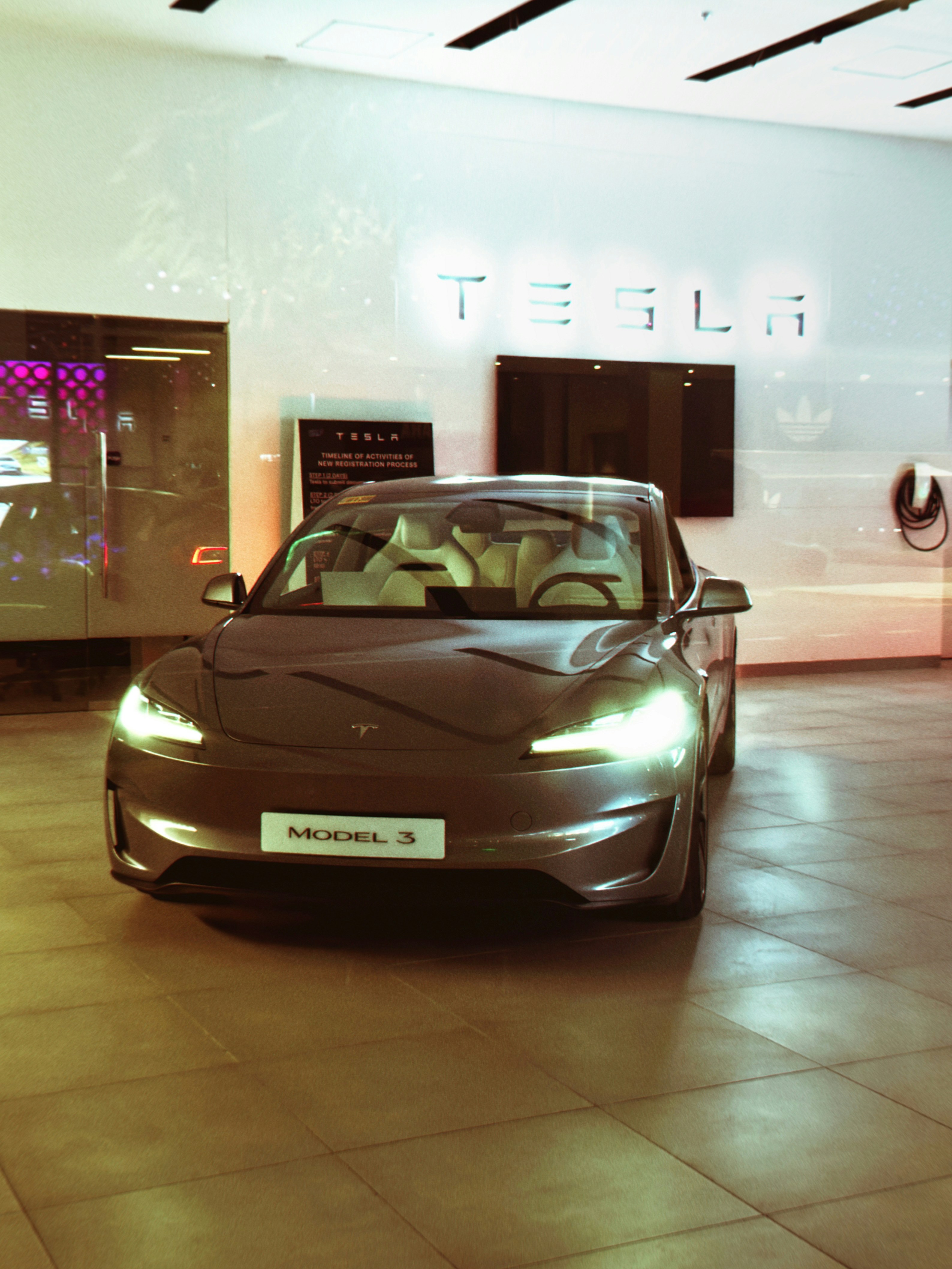 A tesla model 3 is displayed inside a showroom.