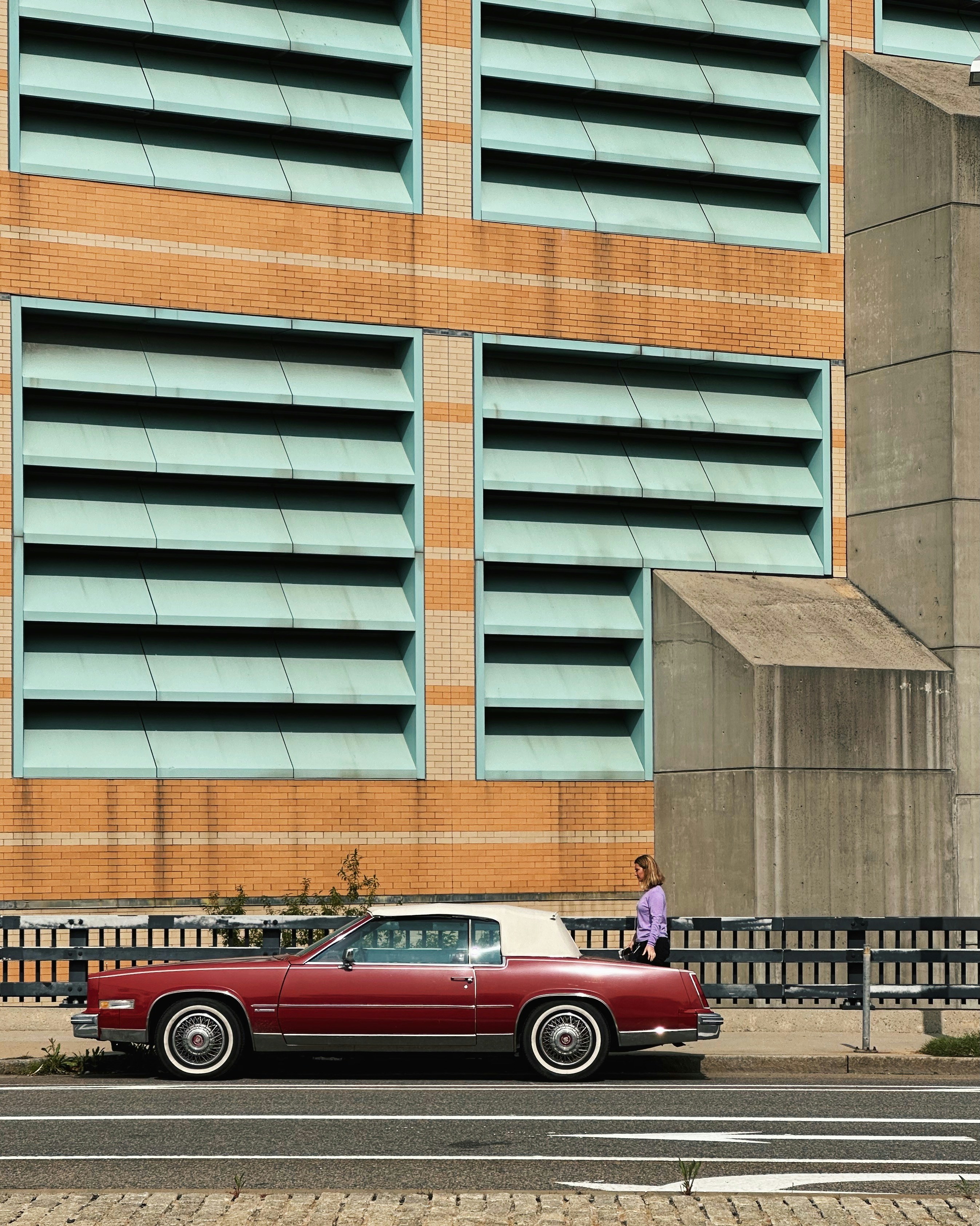 A classic car parks next to a modern building.