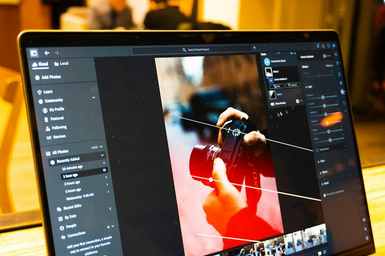 A person editing a photo on a laptop with color correction sliders visible on screen
