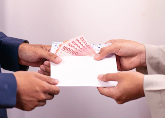 A person is giving money in an envelope