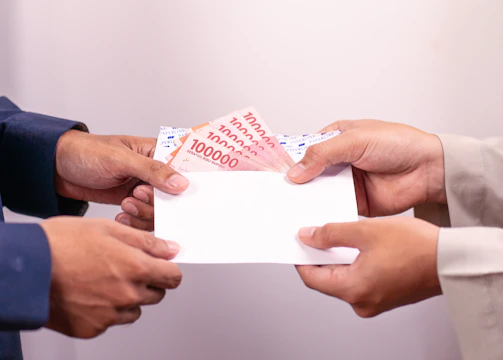 A person is giving money in an envelope