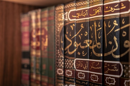 Books with arabic writing are displayed on a shelf.