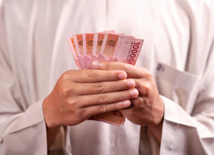 Hands are holding a bundle of indonesian banknotes.