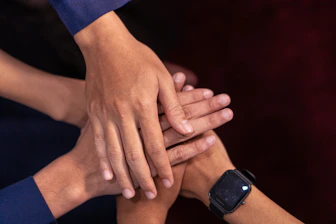 Hands are stacked together, showing teamwork.