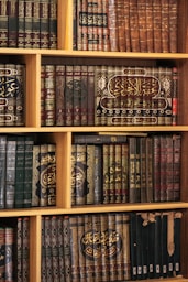 Bookshelf filled with beautifully bound, aged books.